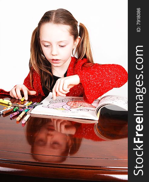 Little girl in a red sweeter sitting on the table and coloring an book
with crayons. Her face mirroring in the table. Little girl in a red sweeter sitting on the table and coloring an book
with crayons. Her face mirroring in the table.