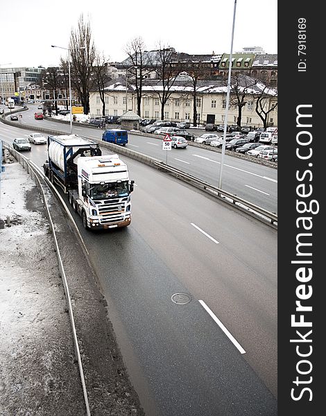 Cars and trailers drive downtown in the Norwegian capital Oslo. The pollution shows on the snow. The Norwegian stock exchange in background. Cars and trailers drive downtown in the Norwegian capital Oslo. The pollution shows on the snow. The Norwegian stock exchange in background.