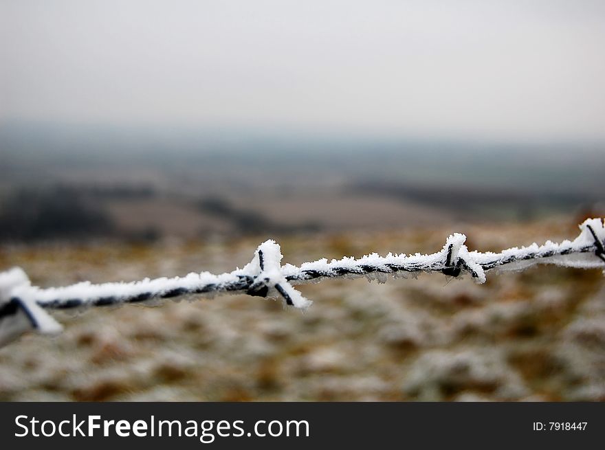 Frozen barbed wire at Uffington White Horse Hill, near Oxford, England. English meadows as background.