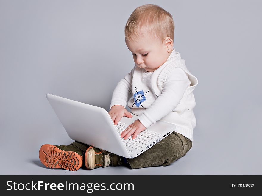 Small baby with white laptop in grey background