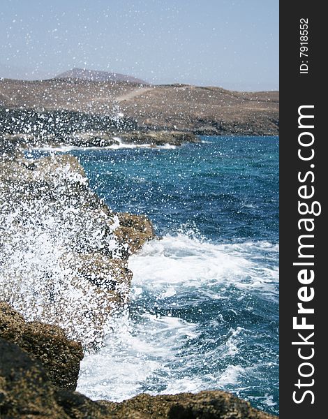 A wave crashes into a mossy rock. A wave crashes into a mossy rock