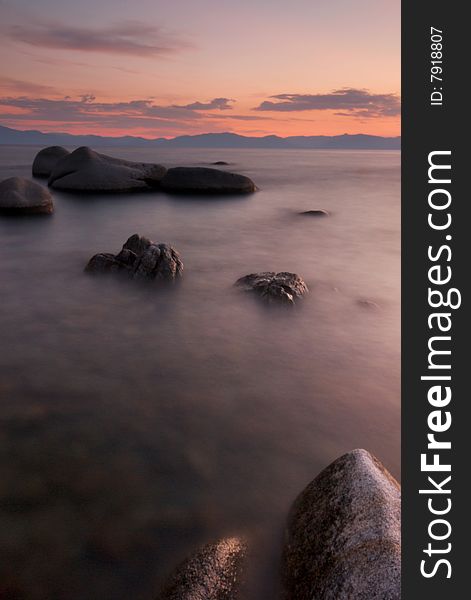 A long exposure of rocks in the surf of lake tahoe at sunset creates an unique, alien landscape. A long exposure of rocks in the surf of lake tahoe at sunset creates an unique, alien landscape