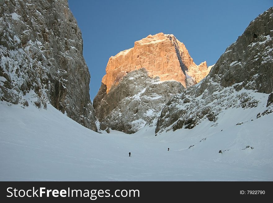 Idyllic winter mountain scene with mountaineers trudging through snow. Jalovec. Julian Alps, Triglav national park, Slovenija. Idyllic winter mountain scene with mountaineers trudging through snow. Jalovec. Julian Alps, Triglav national park, Slovenija