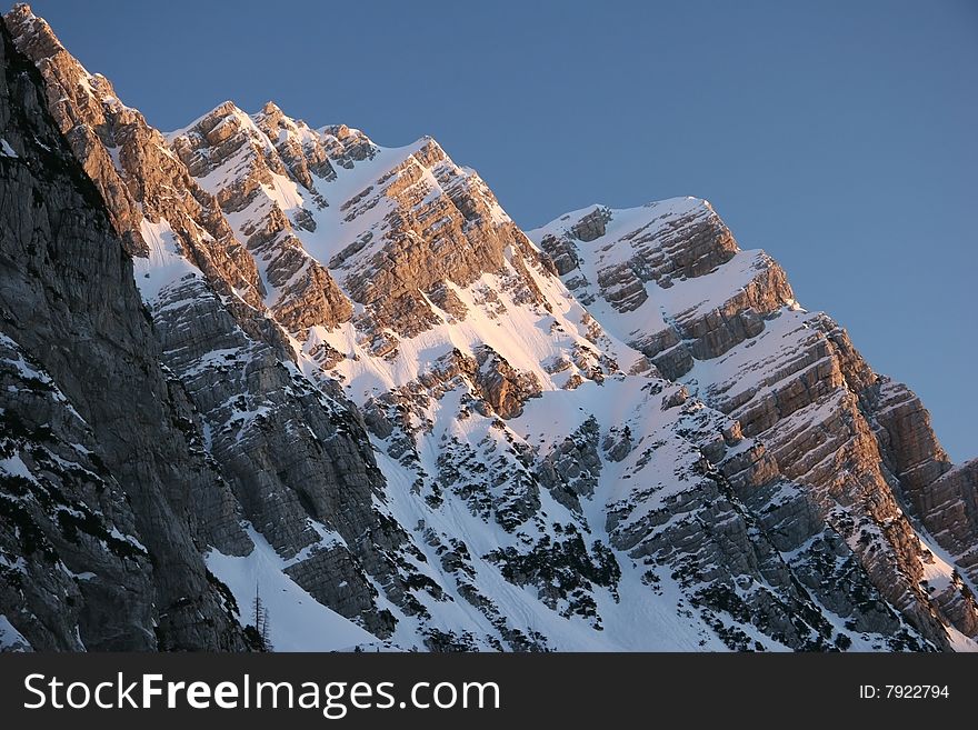 Idyllic winter mountain scene with azure sky over the snowcapped peak.Mountain peak Jalovec. Julian Alps, Triglav national park, Slovenija. Idyllic winter mountain scene with azure sky over the snowcapped peak.Mountain peak Jalovec. Julian Alps, Triglav national park, Slovenija