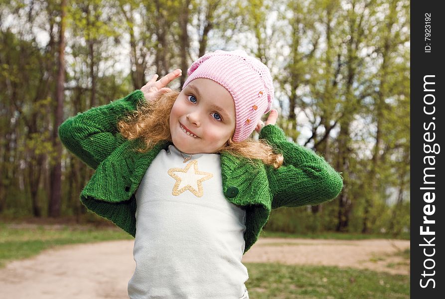 Portrait of the beautiful smiling little girl with long hair in a pink cap in forest. Portrait of the beautiful smiling little girl with long hair in a pink cap in forest