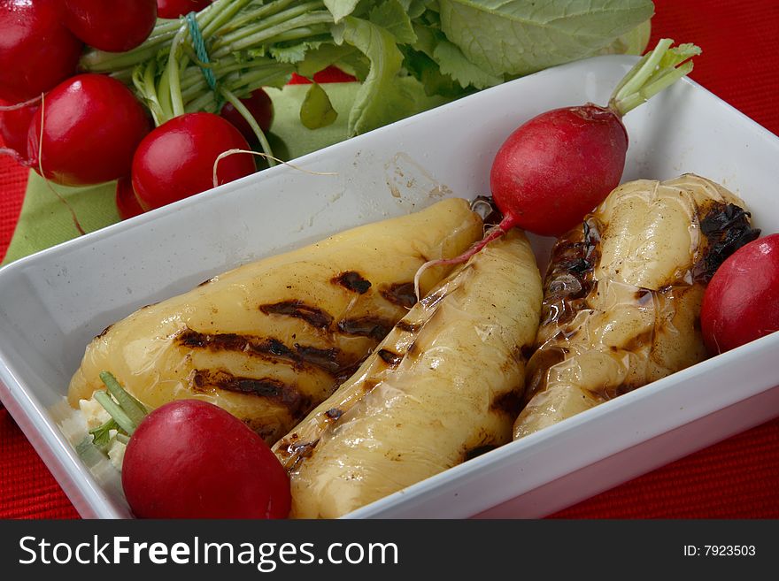 Grilled yellow peppers filled with cheese and fresh radishes on plate