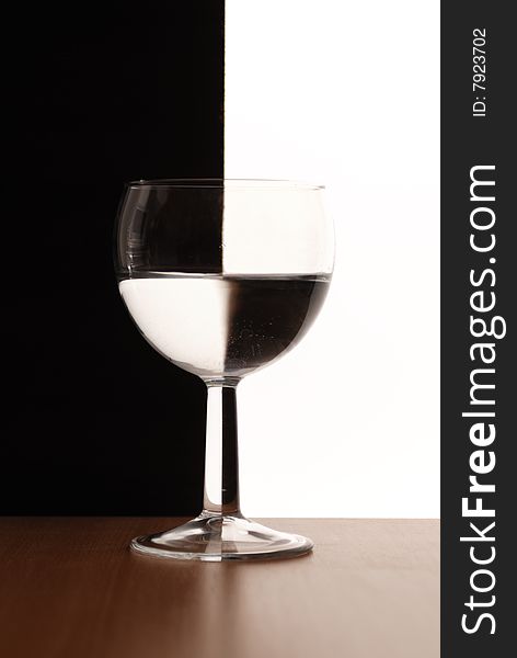 One wine glass in backlight on white and black contrast background