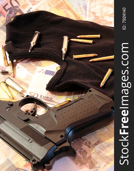 Balaclava, money, gun and bullets showing concept of a robber or terrorist activity. Balaclava, money, gun and bullets showing concept of a robber or terrorist activity