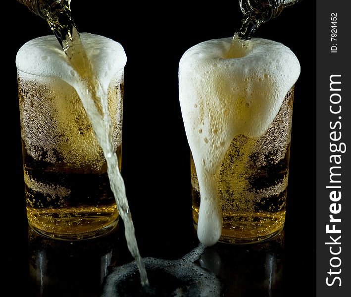A glass of cold beer with foam on a black backgraund