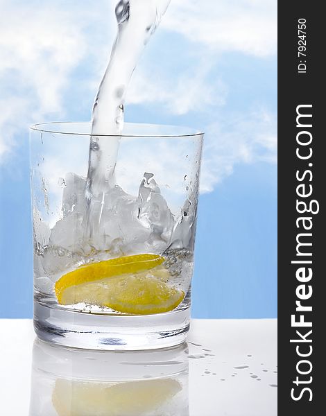 Glass of Water with Lemon on ice and sky background