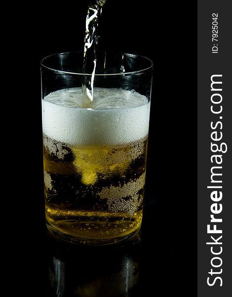 A glass of cold beer with foam on a black backgraund