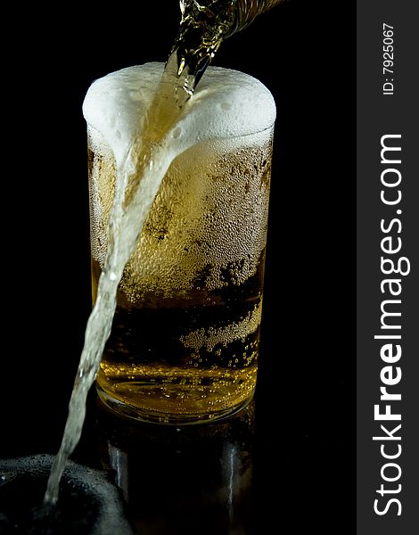 A glass of cold beer with foam on a black backgraund