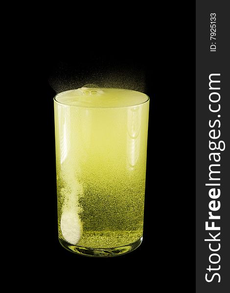 Glasse with yellow water and a tablet.  Isolated on a black background