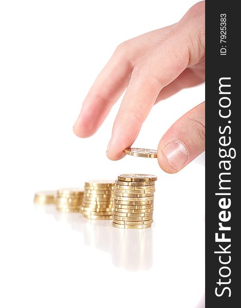 A hand is stacking up coins. Coins are mirrored. Isolated over white. Ideal Businesshot. A hand is stacking up coins. Coins are mirrored. Isolated over white. Ideal Businesshot.