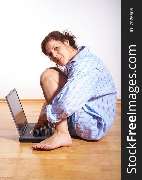 A young woman at home with her laptop sitting on the floor in her new appartment. A young woman at home with her laptop sitting on the floor in her new appartment.