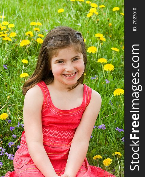 Girl in Red Dress Smiling in Front of Flowers. Girl in Red Dress Smiling in Front of Flowers