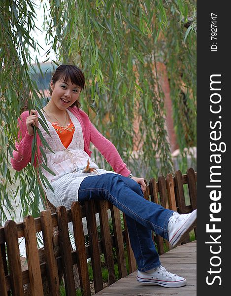 A  beautiful Young girl  sitting on the fence ,from china. A  beautiful Young girl  sitting on the fence ,from china