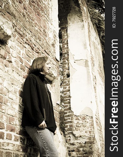 Woman in thought leaning against old brick wall