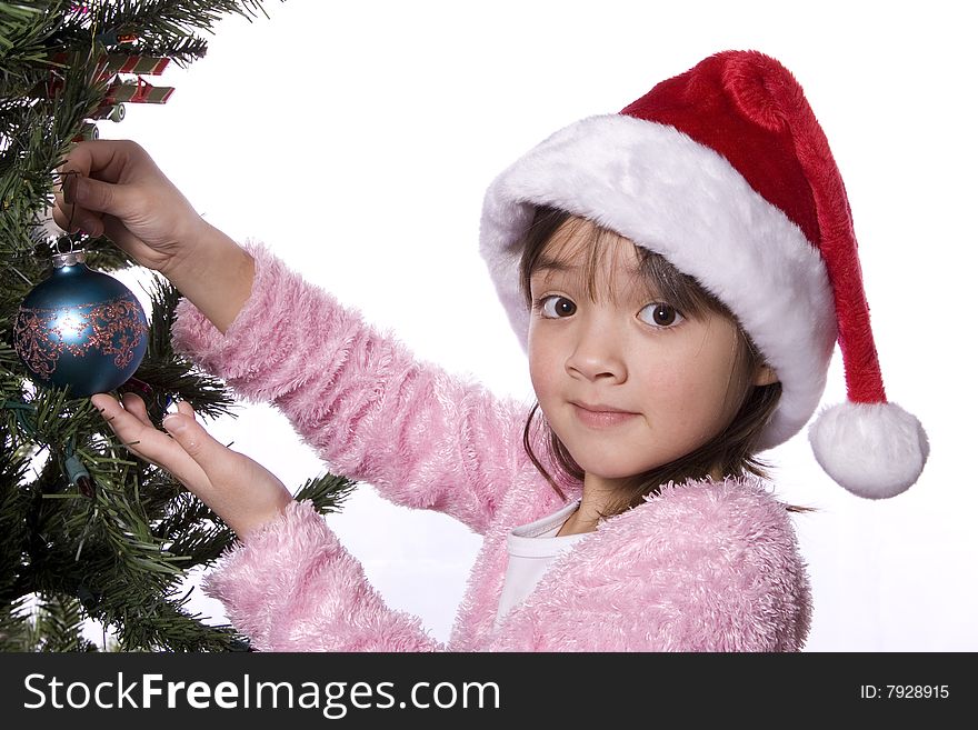 A girl looks into the camera while holding an ornament by a christmas tree. A girl looks into the camera while holding an ornament by a christmas tree.