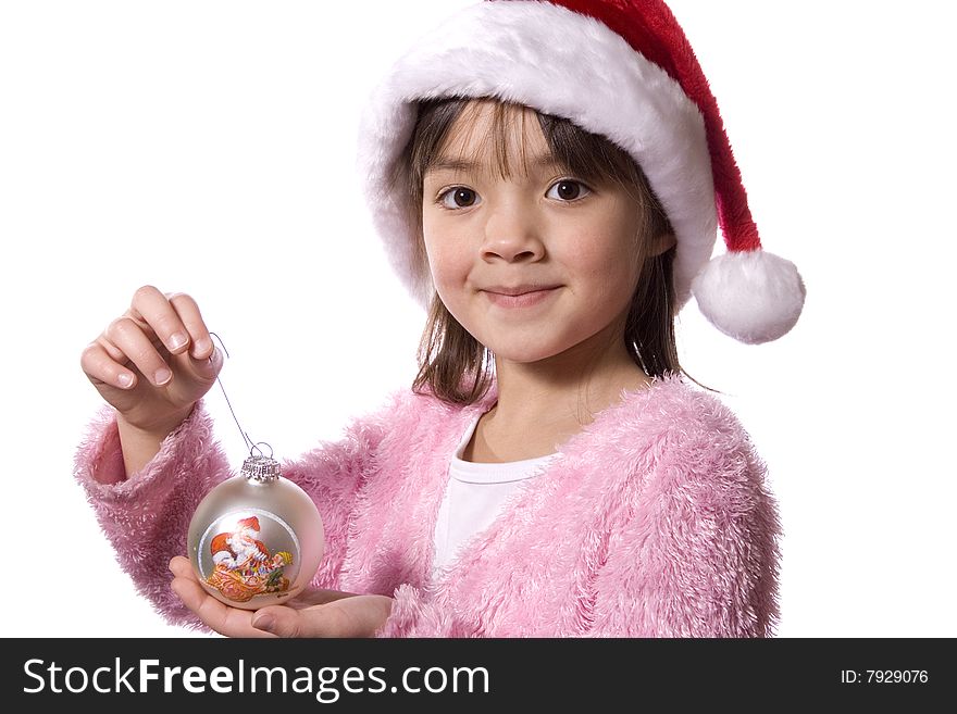 A girl with a santa hat holds a small roundchristmas ornament. A girl with a santa hat holds a small roundchristmas ornament.