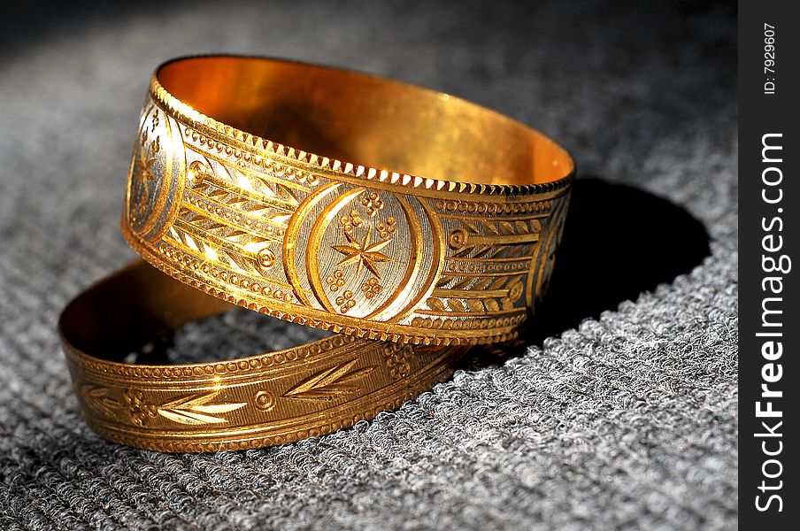 Golden bracelets isolated on textured background.