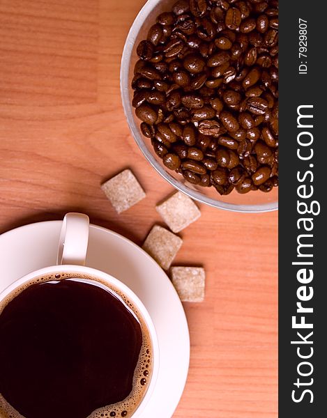 Cup of coffee, beans and sugar on wooden table