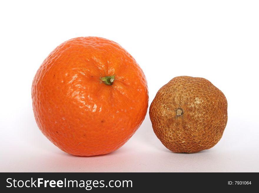 A fresh and a desiccated tangerine alongside each other. A fresh and a desiccated tangerine alongside each other