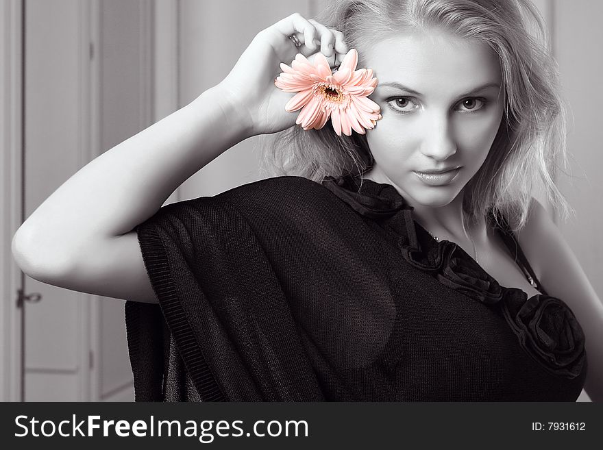 Attractive young woman holding gerbera and looking at camera