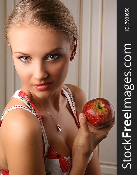 Portrait of attractive young woman holding red apple and looking at camera