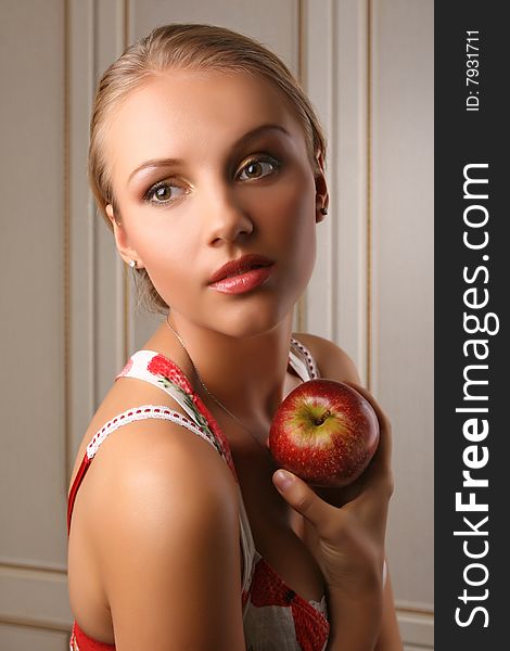 Portrait of attractive young woman holding red apple and looking at camera