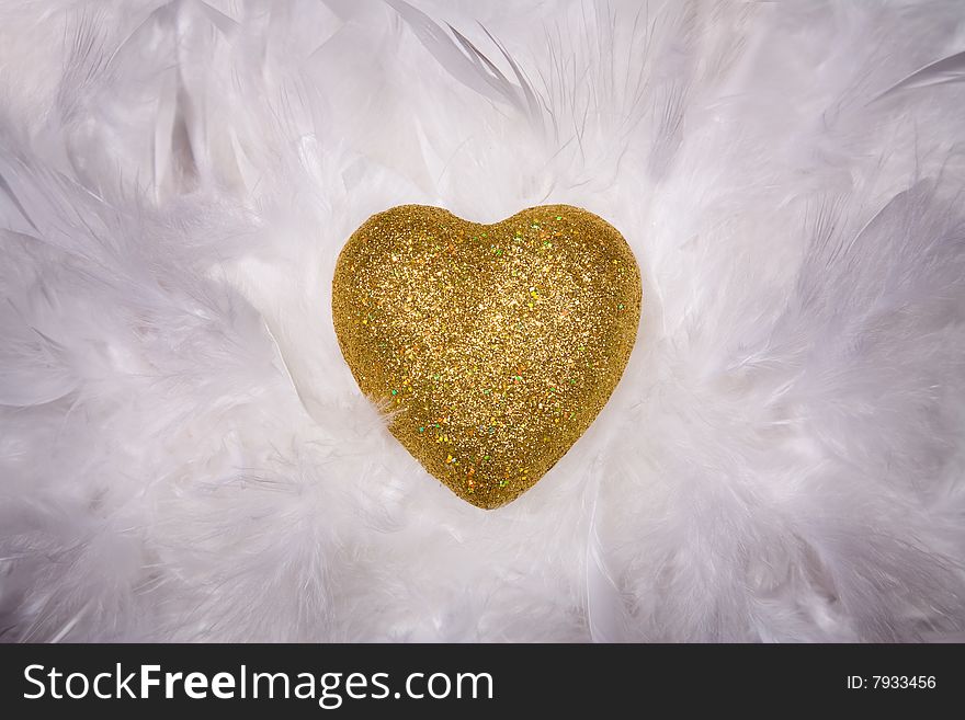 Shiny golden heart over white feathers