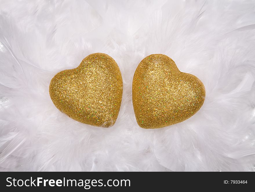 Two golden hearts over white feathers. Two golden hearts over white feathers