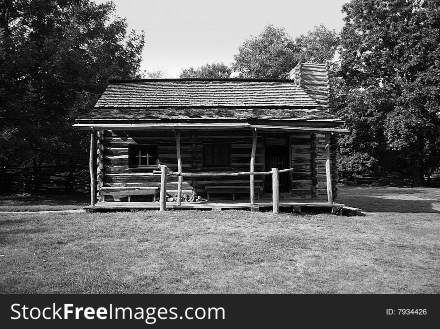 A black & white image of a log cabin in a rural or country setting. A black & white image of a log cabin in a rural or country setting