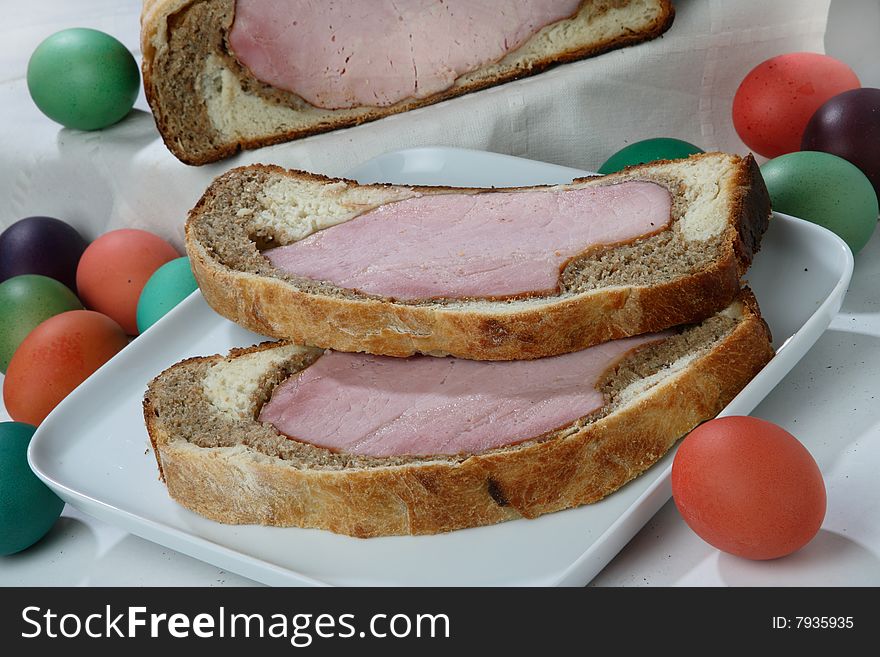 Easter ham on bread with colored eggs on plate