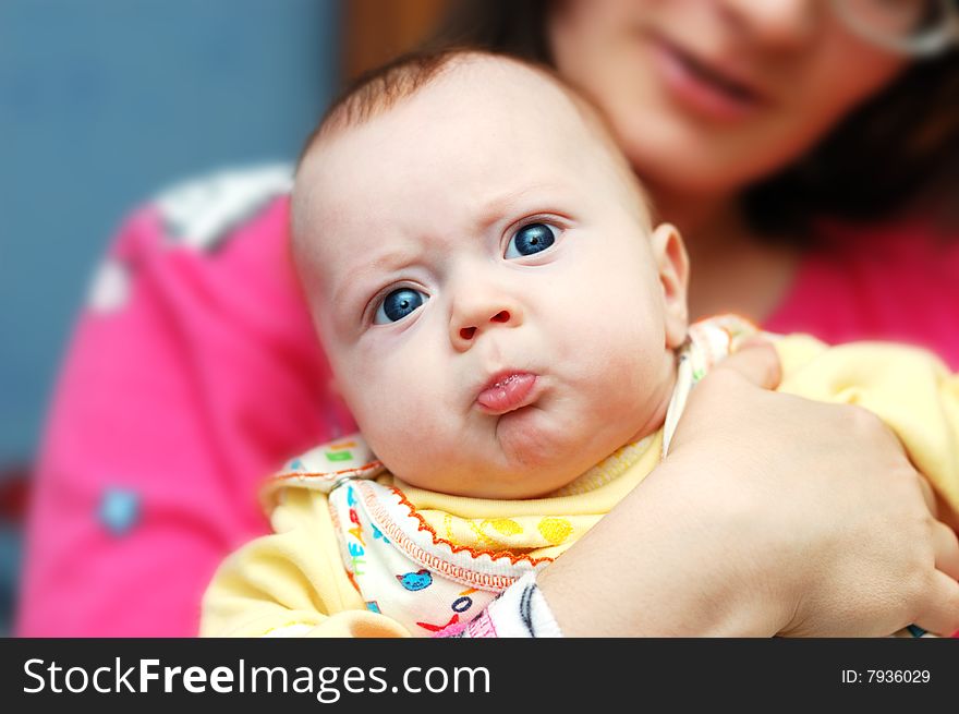 Little 4-month boy pouts his lips in mama's hands
