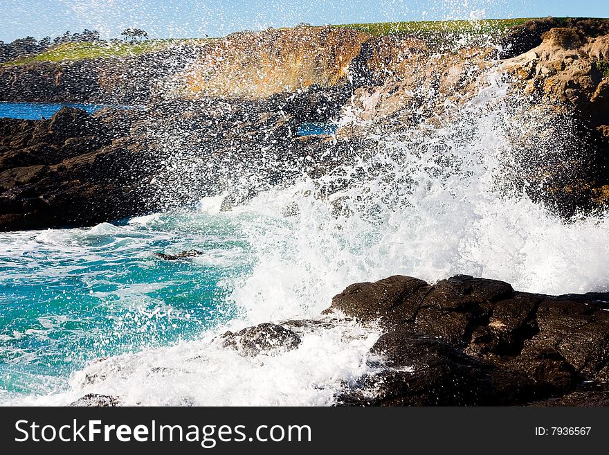 Waves hitting rocky shore on a sunny day