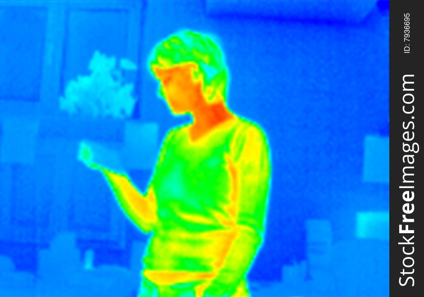 Woman reading a paper in an office. Real infrared (thermic) photo. A thermographic camera is a device that forms an image using infrared radiation and making visible the heat of the model. This image is not a digital effect. Woman reading a paper in an office. Real infrared (thermic) photo. A thermographic camera is a device that forms an image using infrared radiation and making visible the heat of the model. This image is not a digital effect.