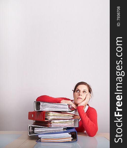 A young and beautiful female worker is stressed with a lot of paperwork in front of her and a pencil in her hair. A lot of copyspace. A young and beautiful female worker is stressed with a lot of paperwork in front of her and a pencil in her hair. A lot of copyspace.