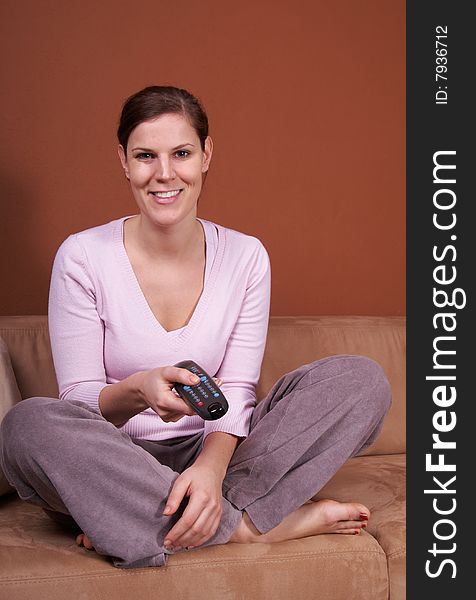 A young woman sits in front of a TV with the remote control in her hand on a couch. A young woman sits in front of a TV with the remote control in her hand on a couch.