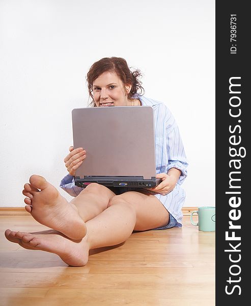 A young woman with a laptop on the floor at home. A young woman with a laptop on the floor at home.