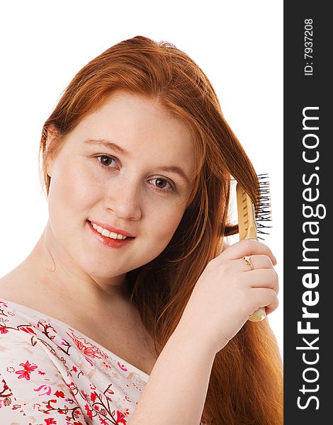 The young beautiful woman combs long red hair, smiles, on a white background