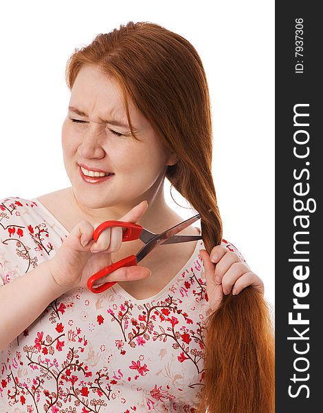 The young beautiful woman cuts red long hair, is afraid, on a white background