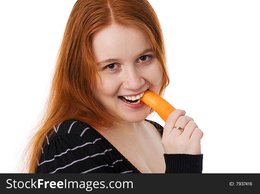 The young beautiful woman with long red hair eats a carrot. The young beautiful woman with long red hair eats a carrot