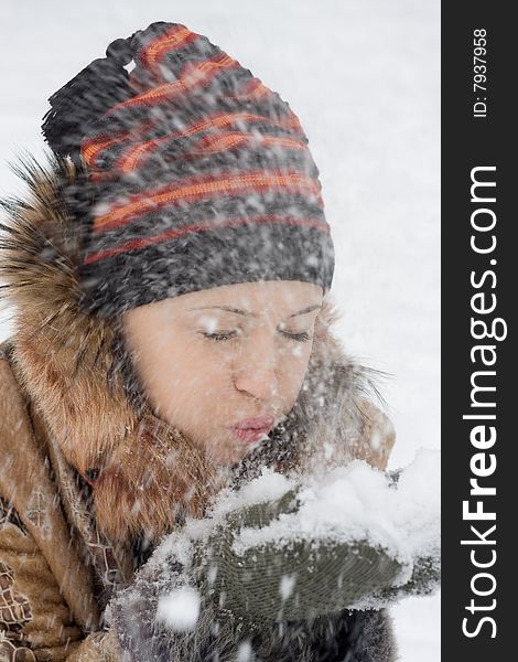 Young beautiful woman walking in the park and  blowing on snow. Young beautiful woman walking in the park and  blowing on snow