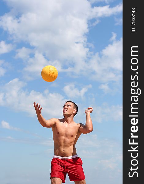 Athletic guy playing volley-ball on the beach