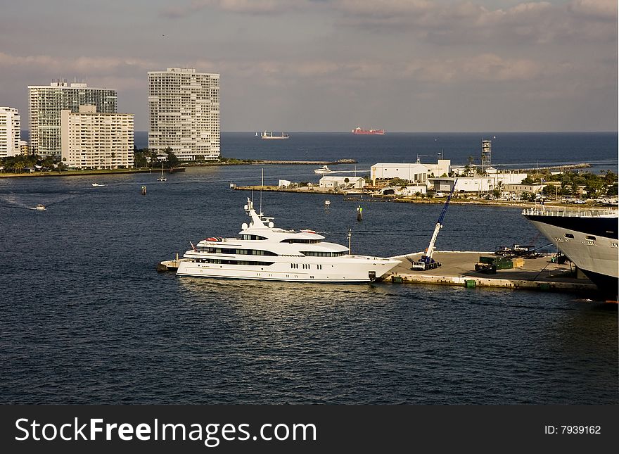 A nice white yacht anchored at a busy harbor. A nice white yacht anchored at a busy harbor