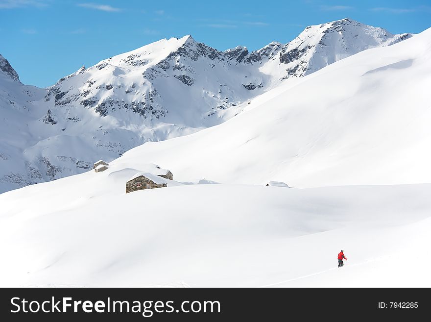 Snowboarder goes downhill over a snowy mountain landscape. Gressoney, Val d'Aosta, Italy. Snowboarder goes downhill over a snowy mountain landscape. Gressoney, Val d'Aosta, Italy.