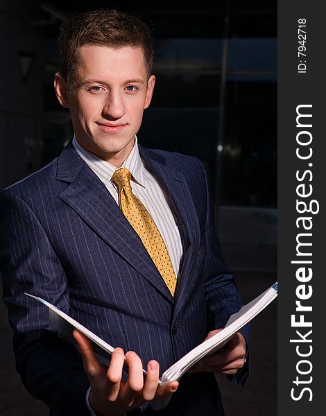 Young friendly businessman with folder outdoors