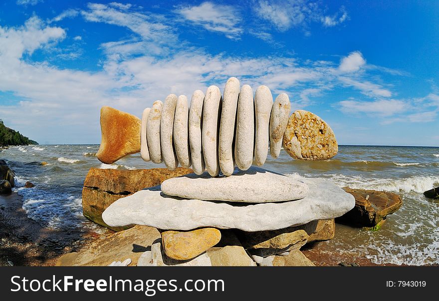 Stone fish on seacoast at midday in the summer