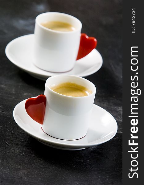 Espresso served on heart shaped cup on coffee beans